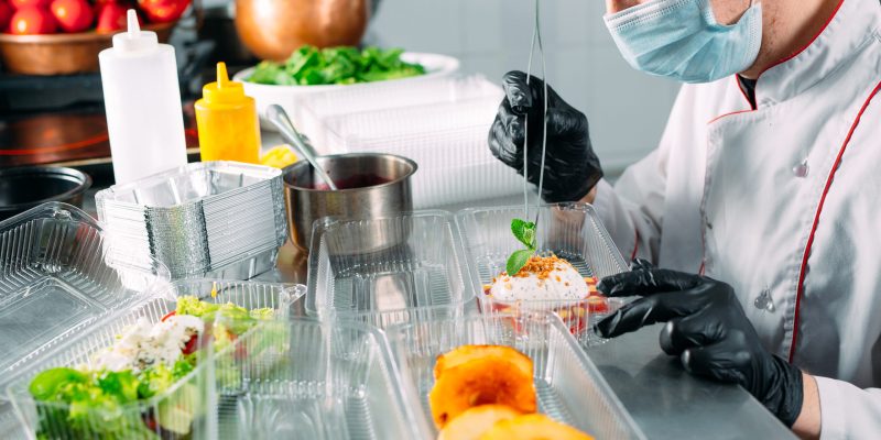 Food delivery in the restaurant. The chef prepares food in the r Food delivery in the restaurant. The chef prepares food in the restaurant and packs it in disposable dishes
